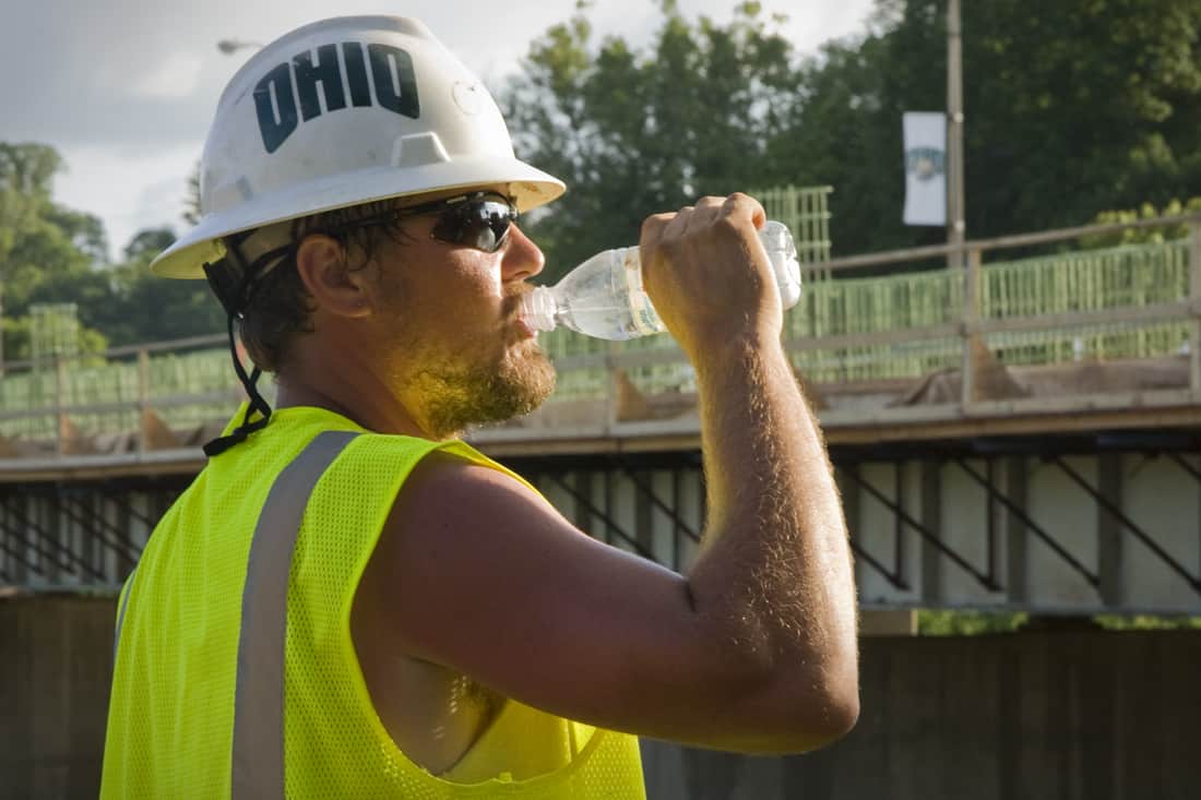 un trabajador de la construcción bebe de una botella de agua