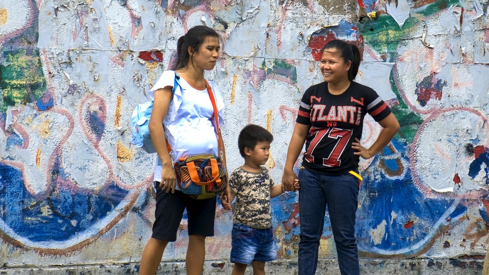 Dos mujeres y un niño en una parada de autobús