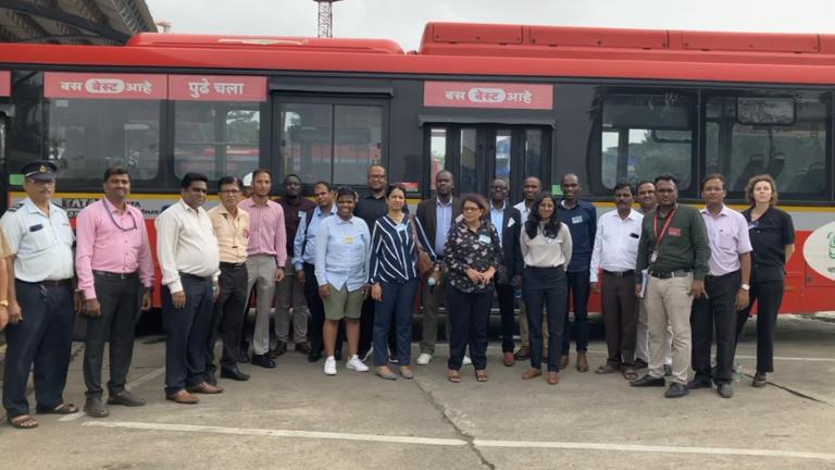 Los participantes en el intercambio Peer to Peer de UrbanShift frente a un autobús de emisiones cero en Bombay.