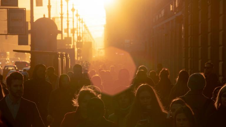 gente caminando por una calle de la ciudad al sol