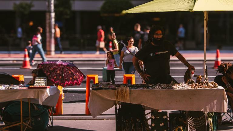 un vendedor ambulante se coloca bajo una sombrilla para darse sombra