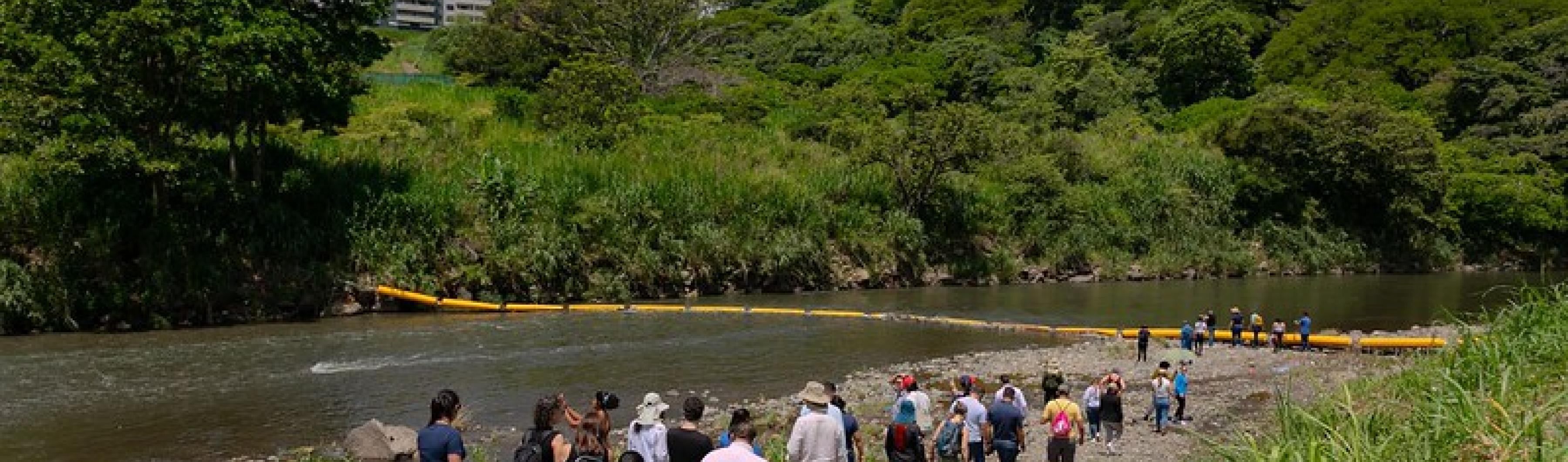 Participantes en la Costa Rica City Academy caminan por las orillas del río Virilla para ver la barrera de plástico que atrapa los residuos.